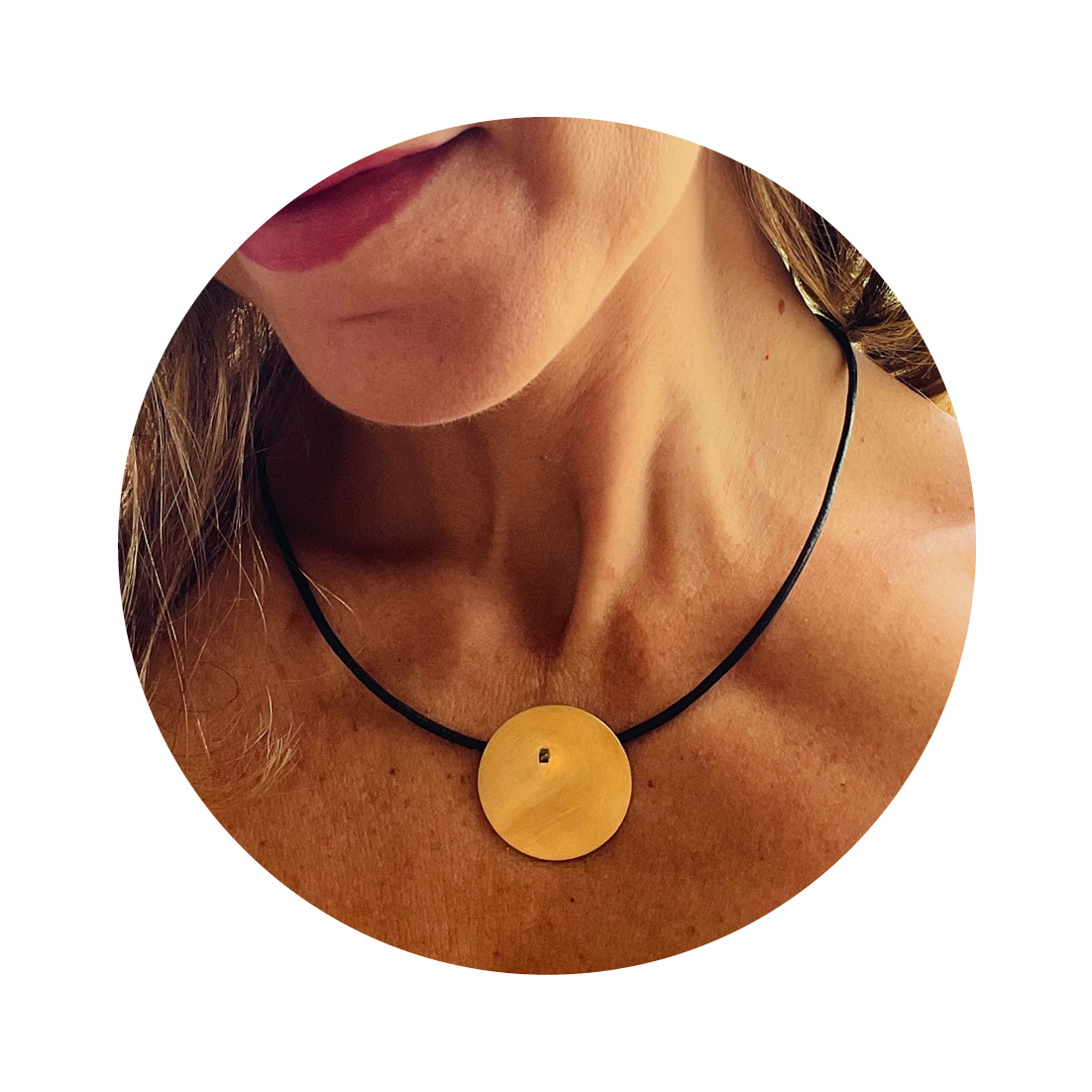 O Colar una Or é feito com fio de couro preto, com pingente em chapa circular fosca, banhada de ouro 750 e sustentada por um pino quadrado, banhado em ródio negro.