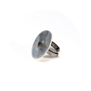 O Earcuff una Ar é feito com fita de prata banhada em ródio negro e tem chapa circular fosca, conectada a um pino quadrado, também banhado em ródio negro.