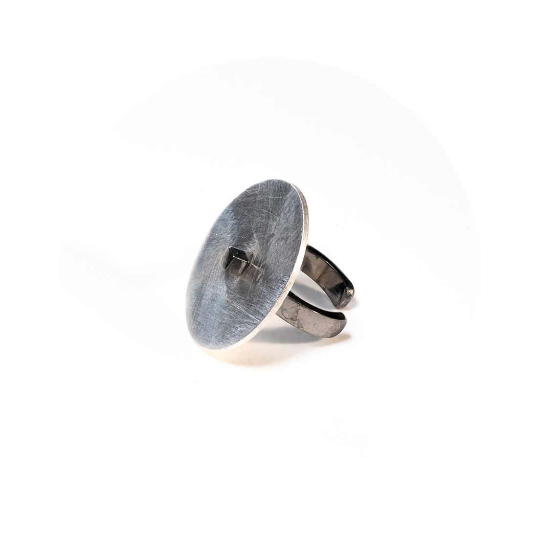 O Earcuff una Ar é feito com fita de prata banhada em ródio negro e tem chapa circular fosca, conectada a um pino quadrado, também banhado em ródio negro.