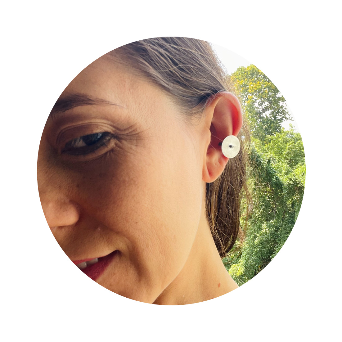 O Earcuff una Ar é feito com fita de prata banhada em ródio negro e tem chapa circular fosca, conectada a um pino quadrado, também banhado em ródio negro.