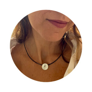 O Colar una Ar é feito com fio de couro preto, com pingente em chapa circular fosca, sustentada por um pino quadrado, banhado em ródio negro.